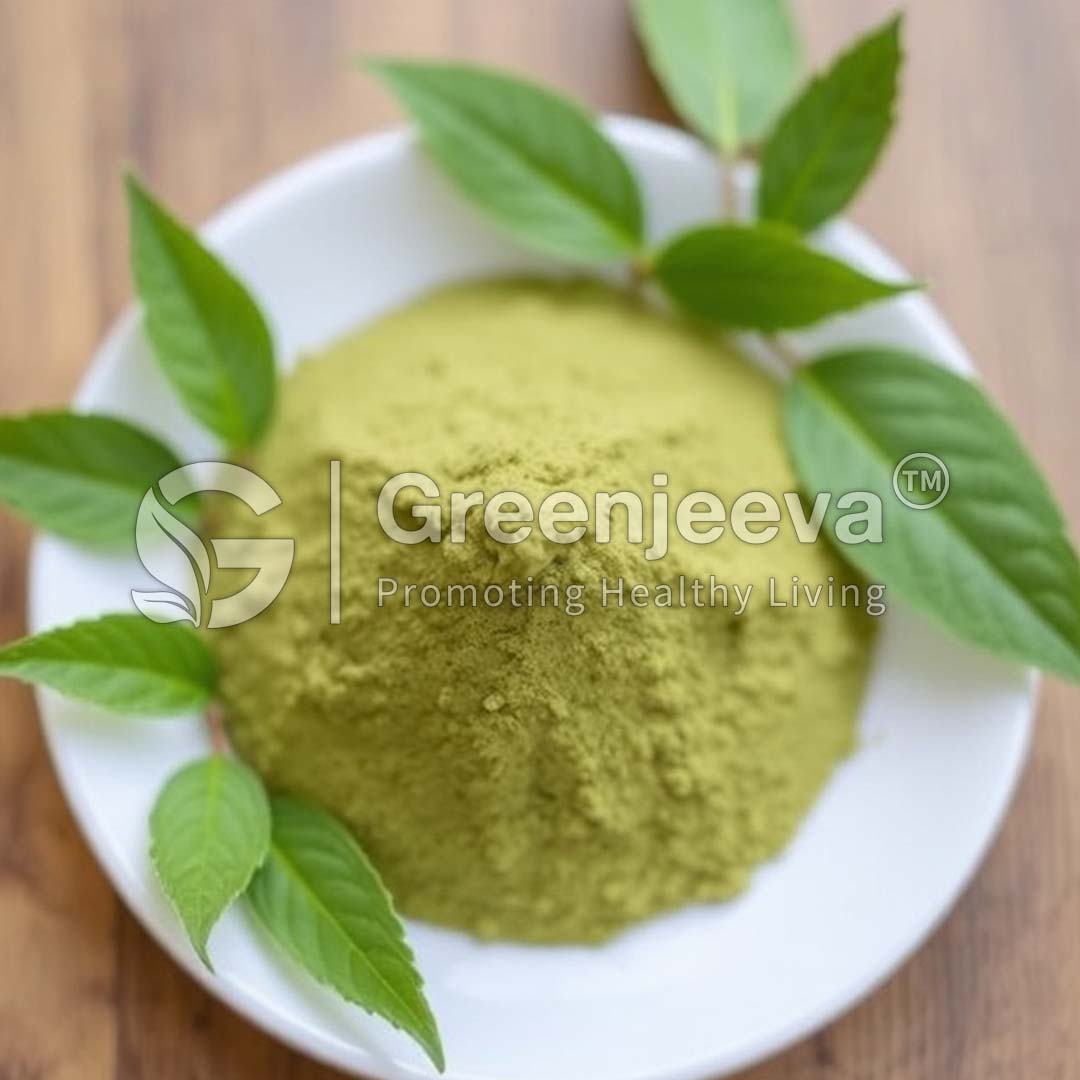 A small bowl filled with Green Tea Extract Powder surrounded by fresh green leaves on a wooden surface.
