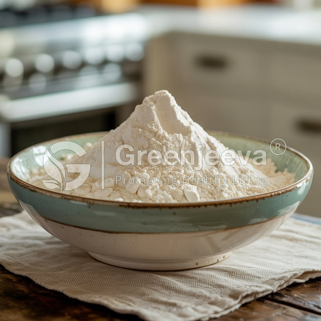 A mound of flour fills a decorative bowl, set on a textured cloth, with a kitchen background softly blurred.