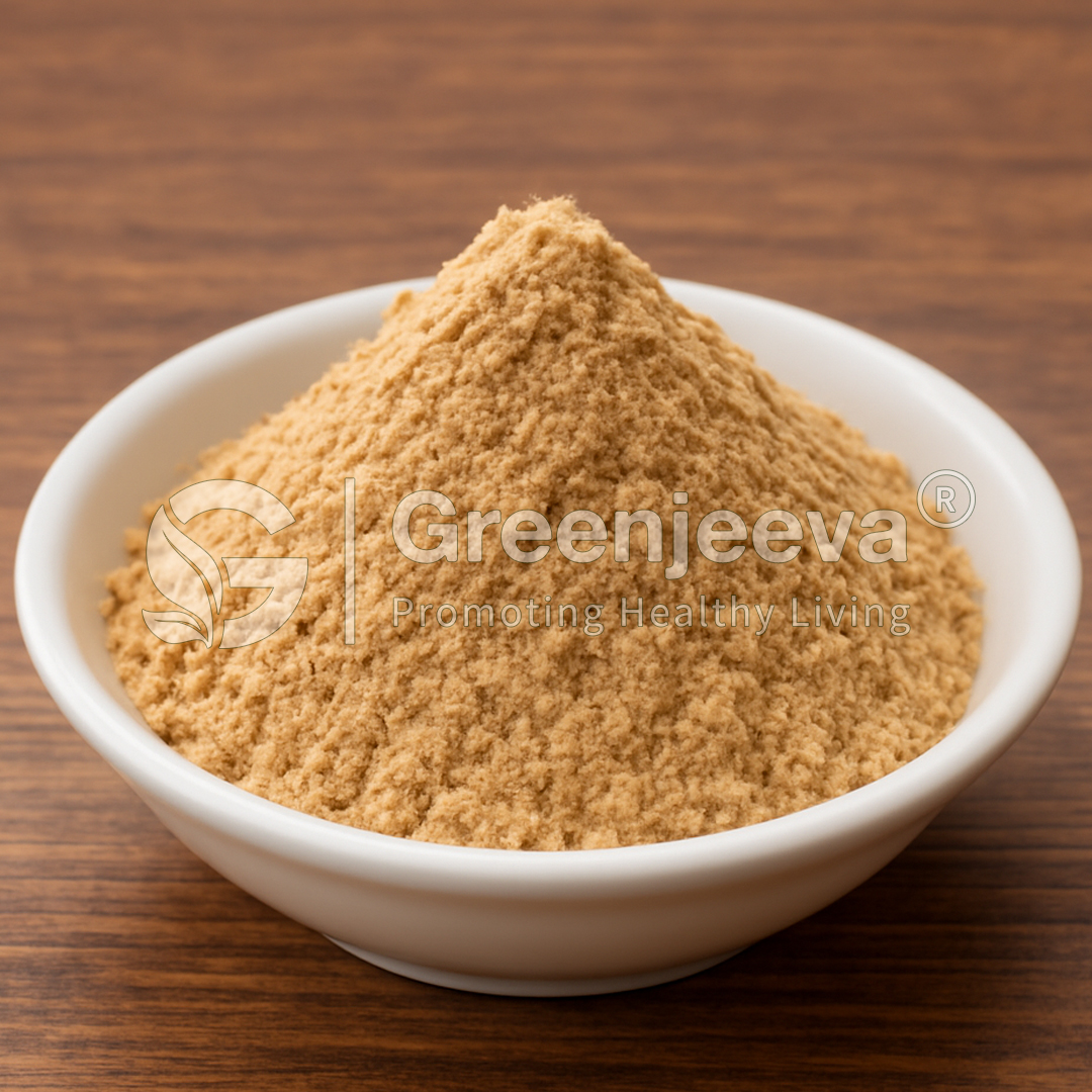 A small white bowl filled with a mound of fine, green lipped mussel powder on a wooden surface, branded with Greenjeeva logo.