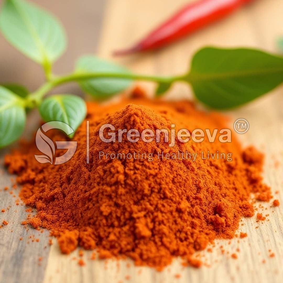 A vibrant mound of Organic Chipotle Chili Pepper Powder sits on a wooden surface, accompanied by fresh green leaves, emphasizing healthy cooking.