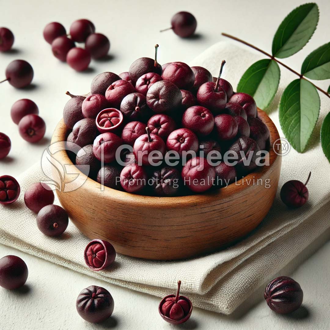 A wooden bowl overflowing with small, dark purple fruits, surrounded by scattered fruits and green leaves on a light fabric backdrop.