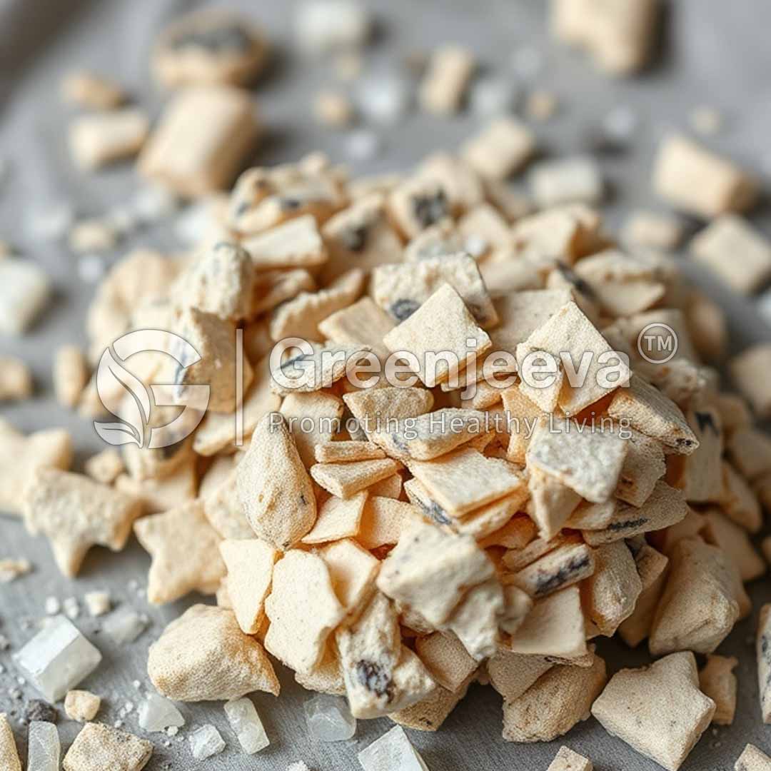 A close-up of a pile of small, irregularly shaped dried fruit pieces scattered with coarse salt on a light surface.